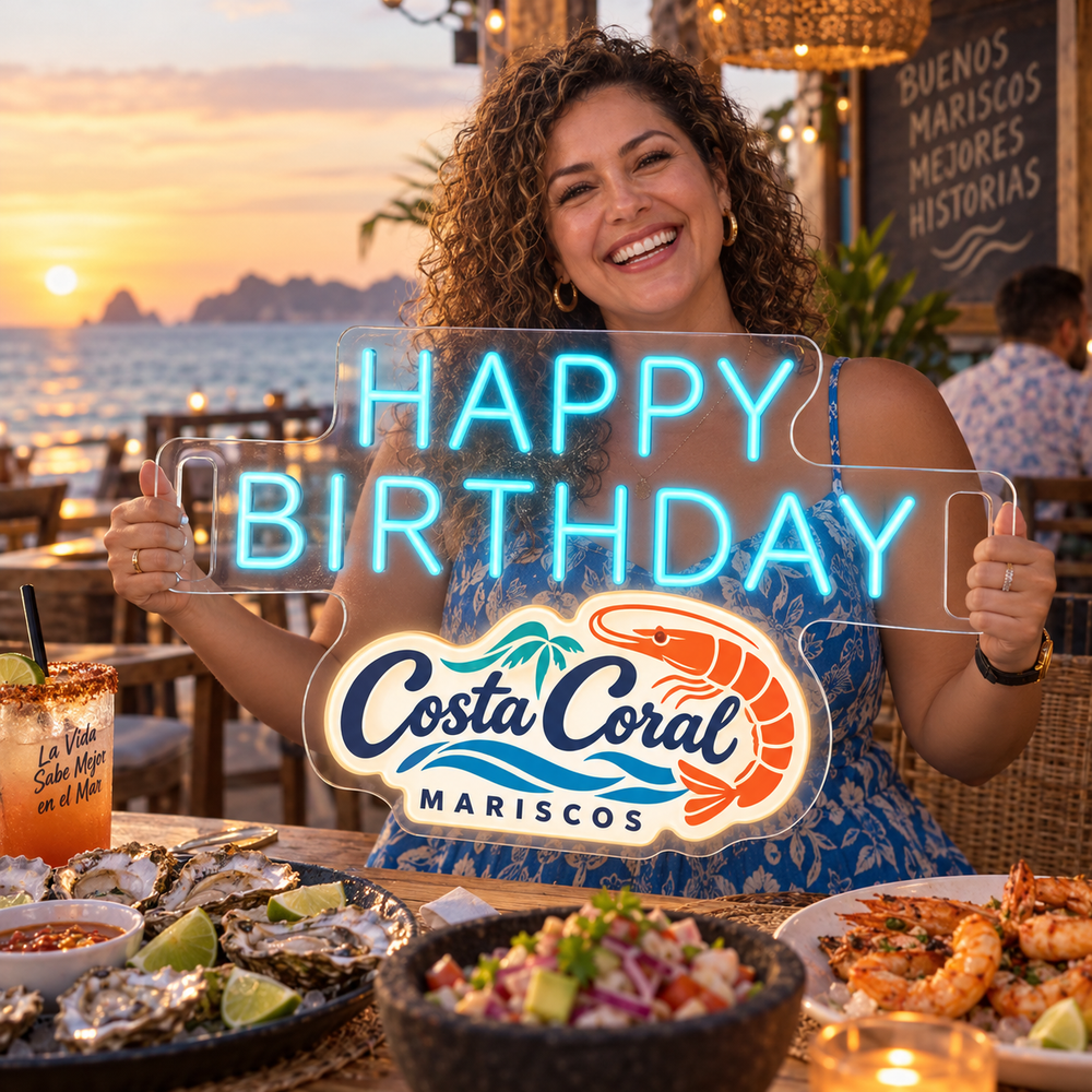 Clienta celebrando su cumpleaños con el letrero Happy Birthday azul con logo de marisquería frente al mar